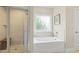 Bright bathroom featuring a bathtub and a separate shower with tiled walls and a glass door at 21 Boots Dr, Angier, NC 27501