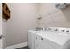 Functional laundry room with washer, dryer, wire rack shelf, and dark vinyl flooring at 21 Boots Dr, Angier, NC 27501