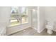 Well-lit bathroom with a glass-enclosed shower, toilet, and a window offering a view of the outdoors at 220 Needle Park Dr, Cary, NC 27513