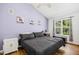 Bedroom with wood floors, window, and light purple accent wall decorated with landscape paintings at 229 White Oak Farm Dr, Willow Springs, NC 27592