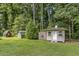 View of storage buildings and a greenhouse in the backyard of this rural property at 229 White Oak Farm Dr, Willow Springs, NC 27592