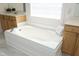 Bright bathroom features soaking tub, white cabinets, and marble tile flooring at 25 Ruth Cir, Fuquay Varina, NC 27526