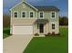 Charming two-story home featuring a two-car garage, manicured lawn, and a combination of beige and green siding at 273 Johnson Ridge Way, Four Oaks, NC 27524