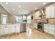 Open kitchen with stainless steel appliances, white cabinets, and modern lighting at 3021 Lawson Walk Way, Rolesville, NC 27571