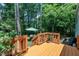 View of wood back deck area surrounded by trees and an umbrella-covered seating area at 320 Bainbridge Cir, Garner, NC 27529