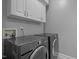 Laundry room featuring modern side-by-side washer and dryer with white upper cabinets at 3902 Stags Leap Cir, Raleigh, NC 27612