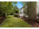 A white home with a stone chimney and screened in porch overlooks a lush backyard at 4315 Sugar Pine Ln, Durham, NC 27705