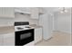 Well-lit kitchen featuring white appliances and cabinets, with direct access to the dining room and adjacent refrigerator at 4825 Windbreak Ln, Raleigh, NC 27616