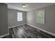 A clean bedroom featuring wood-look floors, paneled walls, two windows, and neutral paint at 511 Commonwealth St, Durham, NC 27703