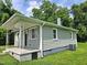 Exterior showing the covered porch, green siding, manicured lawn, and air conditioning unit at 511 Commonwealth St, Durham, NC 27703