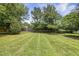 Large, grassy backyard is surrounded by trees and a wooden fence, perfect for outdoor activities at 5317 Peacenest Dr, Raleigh, NC 27610