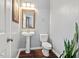 This powder room features a pedestal sink, neutral walls, wood-look flooring, and a decorative mirror at 5505 Heather Garden Way, Raleigh, NC 27613
