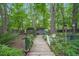 Lush backyard featuring a wooden walkway, garden shed, mature trees, and privacy fence at 5523 Newberry Dr, Raleigh, NC 27609