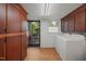 A laundry room providing direct access to the outdoors, ample wooden storage cabinets, and includes a modern washer and dryer at 5523 Newberry Dr, Raleigh, NC 27609