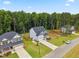 Aerial view of a home with a pristine lawn, paved driveway, and beautiful mature trees at 70 Noble Heart Pl, Fuquay Varina, NC 27526