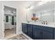 Chic bathroom with blue cabinets, a large mirror, and a view into the serene bedroom at 70 Noble Heart Pl, Fuquay Varina, NC 27526