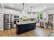 Bright kitchen featuring white cabinets, a dark island, stainless steel appliances and modern lighting at 70 Noble Heart Pl, Fuquay Varina, NC 27526