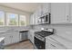 A modern kitchen with white cabinets, stainless steel appliances, and marble countertops and backsplash at 908 Adelphia Rd, Fuquay Varina, NC 27526