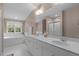 Bright bathroom featuring double vanity, tub, large mirror, and white cabinetry at 92 Summer Dawn, Pittsboro, NC 27312