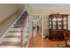 Hallway with hardwood floors and a staircase leading to a cabinet with glass doors at 92 Summer Dawn, Pittsboro, NC 27312