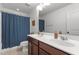 Bright bathroom with a double vanity, dark wood cabinets, and a shower/tub combination behind a blue curtain at 9302 Nellman Ln, Raleigh, NC 27617