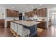 A kitchen island with seating, granite countertops, wood floors, and brown cabinets at 9302 Nellman Ln, Raleigh, NC 27617