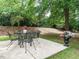 Outdoor patio with a table, chairs, and elegant flower pots, surrounded by lush greenery and mature trees at 101 Lake Tillery Dr, Cary, NC 27519