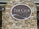 Close-up of 'The Club at Traditions' sign, set against a textured stone wall at 1013 Poppy Fields Ln, Wake Forest, NC 27587