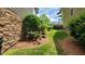 Side yard featuring a stone wall, lush landscaping, and a manicured lawn between homes at 1016 Dotson Way, Apex, NC 27523