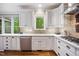 Bright kitchen featuring white cabinets, stainless steel appliances, and a window overlooking the trees at 105 Gorge Ct, Cary, NC 27518