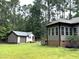 Sprawling backyard with a view of the accessory building and the home's window-enclosed sunroom at 105 Perry Ln, Zebulon, NC 27597