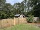 View of the backyard with shed, wooden fence, and lush trees at 105 Perry Ln, Zebulon, NC 27597