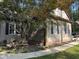 Tan home with brick foundation and beautifully landscaped yard features a sidewalk and bench at 105 Perry Ln, Zebulon, NC 27597
