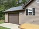 Garage exterior featuring a tan siding, black shutters, and a brown garage door at 105 Perry Ln, Zebulon, NC 27597