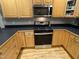 Well-lit kitchen with stainless steel appliances, wooden cabinets, and black countertops, perfect for cooking enthusiasts at 105 Perry Ln, Zebulon, NC 27597
