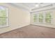 Bedroom with tray ceiling, neutral carpeting, three windows with blinds, and neutral paint at 108 Teagan Ct, Chapel Hill, NC 27516