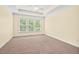 A carpeted bedroom features a tray ceiling with fan and a window with natural light at 108 Teagan Ct, Chapel Hill, NC 27516