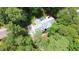 Aerial view of a home surrounded by mature trees, featuring a patio with outdoor seating and a blue umbrella at 12037 Deer Run, Raleigh, NC 27614