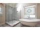 Bright bathroom featuring a glass enclosed shower and separate soaking tub with decorative window at 12037 Deer Run, Raleigh, NC 27614