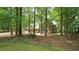 View of a red brick home with blue shutters, framed by trees and a lush green lawn at 12037 Deer Run, Raleigh, NC 27614