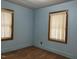 Bedroom with light blue walls, wood trim windows, laminate flooring, and natural light at 129 S Bullock St, Henderson, NC 27536