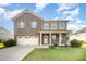 Two-story brick home featuring a well-maintained lawn, a two car garage, and a charming front porch at 1305 Ivey Grove Ct, Fuquay Varina, NC 27526