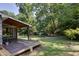Spacious backyard with mature trees, lush green grass, and wooden deck with an adjacent shed at 1613 Euclid Rd, Durham, NC 27713