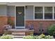 Charming home entrance featuring a gray door, brick accents, and well-manicured landscaping at 1613 Euclid Rd, Durham, NC 27713
