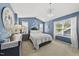 Inviting main bedroom featuring bright blue accent wall, large windows, and a modern chandelier at 1625 Main Divide Dr, Wake Forest, NC 27587