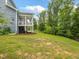 Spacious backyard with a view of the covered porch, green trees, and plenty of space for outdoor activities at 1804 Amberly Ledge Way, Cary, NC 27519