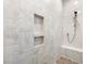 The walk-in shower includes stone tiling, recessed shelving, and a bench at 1804 Amberly Ledge Way, Cary, NC 27519
