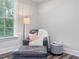 Comfortable sitting area with chair, ottoman, floor lamp, and side table near a bright window at 1804 Amberly Ledge Way, Cary, NC 27519