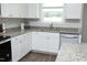 Close up of kitchen showing sink, granite countertop, stainless dishwasher, and white cabinetry at 200 Sweet Violet Dr, Youngsville, NC 27596