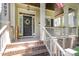 Inviting front porch with brick steps, white railings, a floral wreath on the black door, and a partially visible American flag at 2027 Hopeton Ave, Raleigh, NC 27614